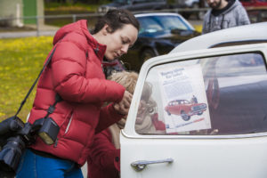 Elle and Denise adhering a flyer to the car window