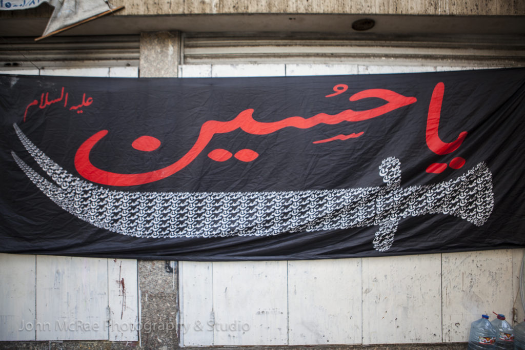 The Shia festival, Ashoura, celebrates the matyrdom of Hussein (son of Ali, grandson of the Prophet Muhammad).  He died in the battle of Karbala in 680 AD.  Many flags and banners are displayed around the city.  Above is "Ya Hussein", written in Arabic.  ©johnmcrae